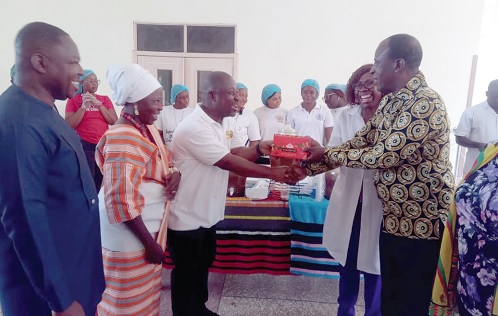 Wisdom Ahadzi (3rd from right), Upper East Regional Director, GTA, presenting a box of chocolates to Samuel Azure Atuba (left), Administrator, Bolgatanga Regional Hospital 