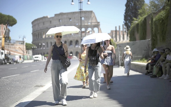 People using umbrellas in hot weather to shelter from the sun while walking past the Colosseum, in Rome People using umbrellas in hot weather to shelter from the sun while walking past the Colosseum, in Rome