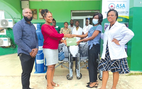 Mary Colette Arthur, (2nd from left ), Tema Manhean Business Centre Manager of ASA Savings and Loans Limited, handing over the items to Dr Anita Ofosu Boateng, Medical Officer, Manhean Polyclinic, while Justice Korsah (left), Kpone Area Manager of ASA Savings and Loans, looks on