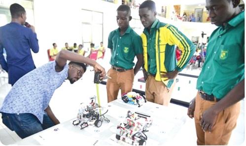 Kojo Anyinam Boateng (left), Executive Judge of the competition, measuring the size of a robot for students of Prempeh College in 2023 Kojo Anyinam Boateng (left), Executive Judge of the competition, measuring the size of a robot for students of Prempeh College in 2023