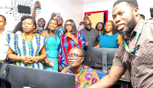 Dennis Tandoh (right), Member of the Instructional Design team, supervising Prof.  Rita Akosua Dickson (seated), to fly a drone. Those looking on include Professor Marian Asantewah Nkansah (left), Director of Student Affairs.