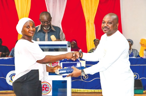 Charles Lwanga Puozuing (right) presenting the scholarship award to one of the beneficiaries 