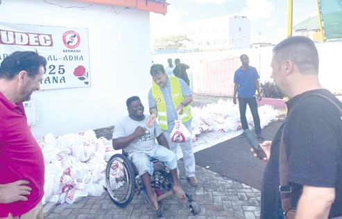 One of the beneficiaries (in wheelchair) receiving a parcel of meat from a volunteer of TUDEC One of the beneficiaries (in wheelchair) receiving a parcel of meat from a volunteer of TUDEC