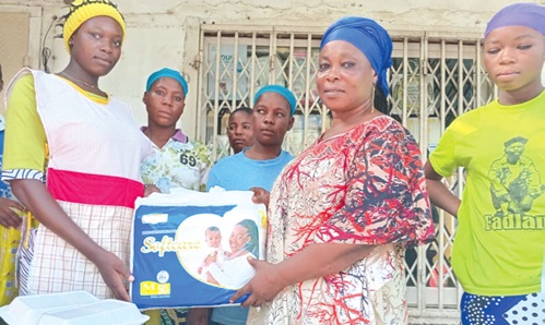 Hajia Kwalebu Fuseinatu Sulemana (2nd from right), Programme Manager, Kunata Voluntary Organisation, presenting a pack of diapers to one of the beneficiaries Hajia Kwalebu Fuseinatu Sulemana (2nd from right), Programme Manager, Kunata Voluntary Organisation, presenting a pack of diapers to one of the beneficiaries