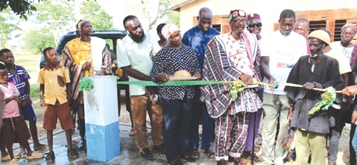 Naba Baba Salifu Atamale Lemyaarum (middle), Paramount Chief of the Bongo Traditional Area, being assisted by other officials to cut the tape to commission the project. INSET: The new water supply system Naba Baba Salifu Atamale Lemyaarum (middle), Paramount Chief of the Bongo Traditional Area, being assisted by other officials to cut the tape to commission the project. INSET: The new water supply system