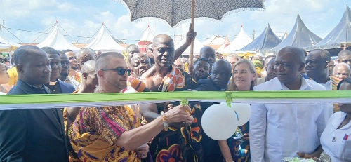 Oyeadieyie Basape Kojo Armah III (middle), Paramount Chief of the Sefwi Bekwai Traditional Area, being assisted by a representative of Mission 318 and other officials to cut the tape to inaugurate the facility