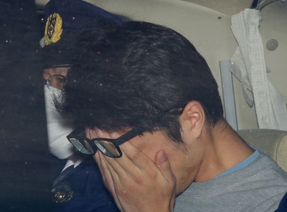 Takahiro Shiraishi covers his face inside a police car in Tokyo, in this photo taken by Kyodo November 2017 and released by Kyodo December 15, 2020. Mandatory credit Kyodo/via REUTERS/File Photo