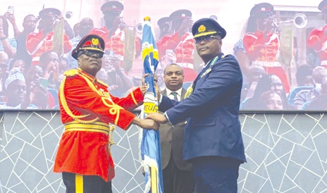Major General Richard Addo Gyane (left), Commandant of KAIPTC, handing over the KAIPTC flag as a sign of authority to his successor, Air Commodore David Anetey Akrong (right), the Deputy Commandant of the KAIPTC, as Brogya Gyenfi, the Deputy Minister of Defence, looks on