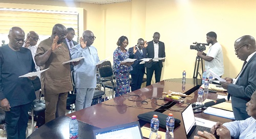 Justice Kwabena Asuman Adu (rtd) [right] swearing in the members of the three committees