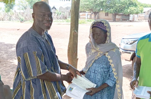 Wumbei Salifu, Director of Natural Resources at BPA, presenting a cheque to Tahiru Fatima, an affected farmer