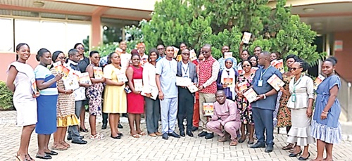 Victor Tawia (middle), Ga West Municipal Director of Education, and his teachers displaying copies of the rabies prevention education materials