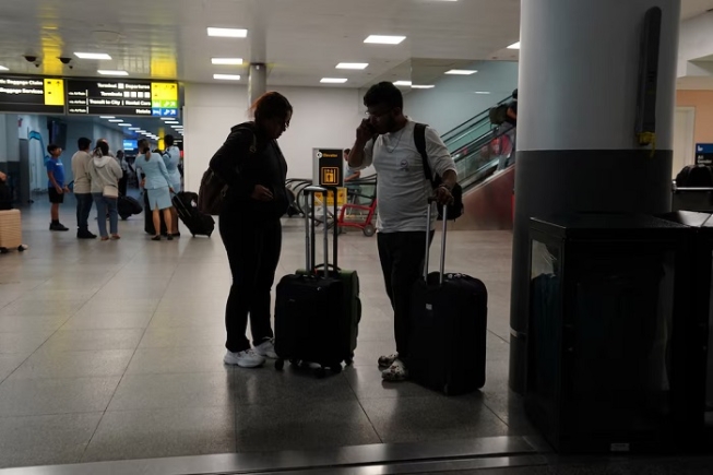 Travelers use a mobile phone at Terminal 8 at John F. Kennedy International Airport in New York, U.S., June 8, 2025. REUTERS/Bing Guan/File Photo