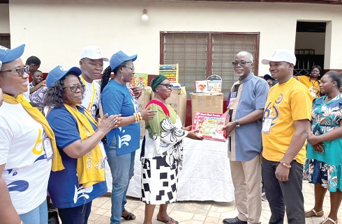 Eric Sey (2nd from right), Ga East Municipal Education Director, presenting one of the items to Dorothy Quansah (5th from left), Proprietor of High Moral International School