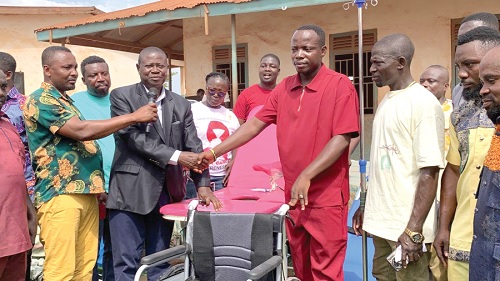 Dominic Bonsu (3rd from right), Assembly Member for Manso Takorase in the Amansie South District, handing over one of the wheelchairs to Yaw Opoku, the District Planning Officer