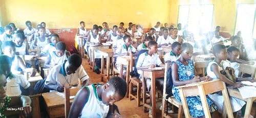 Pupils in one of the congested classrooms with sunlight streaking in from the perforated roof