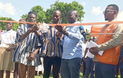 Joshua Baidoo (2nd from right), World Vision Ghana, being assisted by Richard Wulo ( 3rd from right), DCE for Wa West, to cut the tape to inaugurate the office