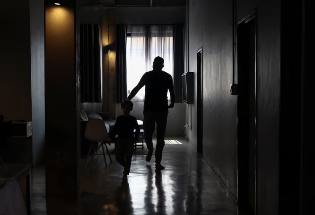 A Palestinian man, one of 130 granted entry to South Africa after initially being denied for not meeting immigration requirements, walks with his child after speaking to Reuters at an undisclosed location in Johannesburg, South Africa, November 14, 2025. REUTERS/Siphiwe Sibeko