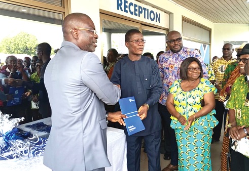 Courage Nunekpeku, Managing Director TDC Ghana Ltd, handing over a copy of the catalogue to Isaac Ashai Odamtten, Board Chairman, TDC