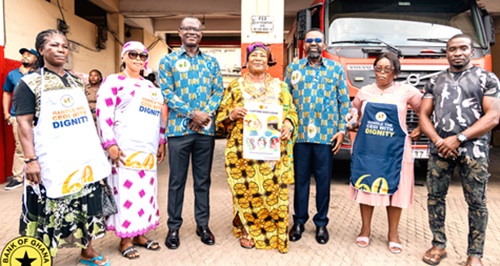 Mercy Naa Afrowa Needjan (middle), President, Greater Accra Markets Association, displaying a leaflet for the campaign in a photograph with Dr Johnson Pandit Asiama (3rd from right), Governor, Bank of Ghana; Dr Zakari Mumuni (3rd from left), First Deputy Governor; and other traders at the Makola Market.