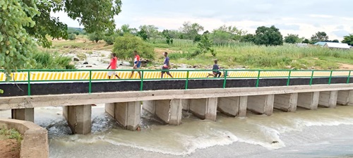Some residents walking on the newly constructed bridge across the Vea Dam spillway