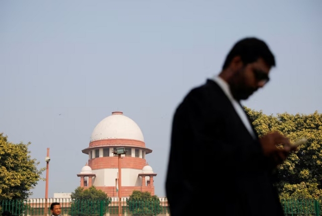 A lawyer looks into his mobile phone in front India's Supreme Court in New Delhi, December 11, 2023. REUTERS/Adnan Abidi/File Photo