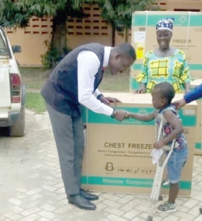 Ignatius Godfred Dordoe, DCE for Shai-Osudoku, presenting a deep freezer to John Teye, a physically-challenged boy