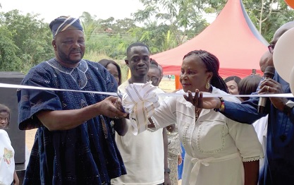 Thomas Adongo Fadola (left), Deputy District Director of Education, Gomoa East District,  and Gladys Osei (right), the Club Patron, cutting the tape to inaugurate the newly renovated classroom block