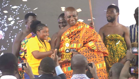 Nana Professor Oheneba Boachie-Adjei Woahene II, Board Chairman, Otumfuo Osei Tutu II Foundation, presenting a plaque to Freda Owusuaa Acheampong, winner of the Otumfuo Community Reading Challenge, amid cheers from the crowd