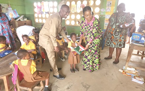 Ewurabena Aubynn (right), MP for Ablekuma North, being assisted by Adamu Musa Kalamu, MCE for Ablekuma North, to present some books to one of the pupils during the visit