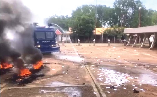 Students burning car tyres and  police spraying hot water to disperse students