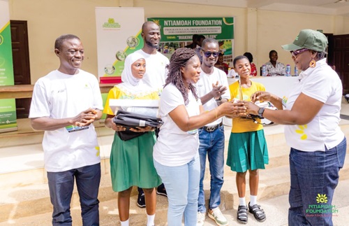 Dinah Asante (right), a Board Member of Ntiamoah Foundation, presenting a trophy to the staff and pupils of New Abirem District Assembly ‘A’ Basic School for emerging as the overall winner of the reading competition. With them is Williams Sarpong, the Programmes Manager of Ntiamoah Foundation.