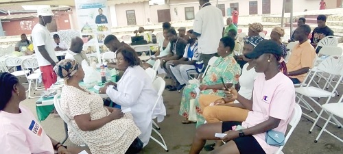 A nurse screening a participant, while others wait for their turn 