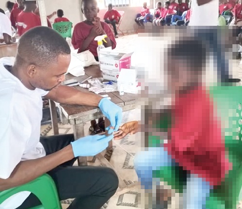 A medical staff member conducting a blood sample collection for a participant in the Obeyeyie Care medical screening and outreach at Dormaa Akwamu 