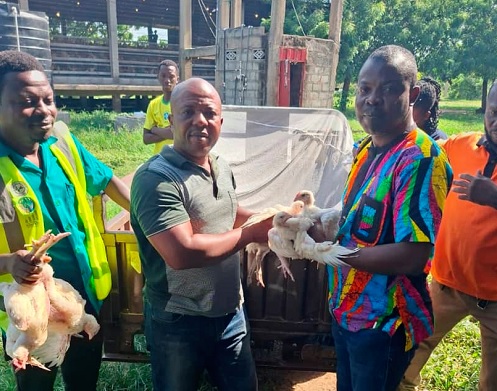 Francis Akumatey Addo (middle), Yilo Krobo Municipal Chief Executive, presenting some of the birds to a beneficiary