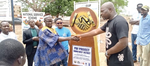 James Ayamwego (right), DCE for Bawku West, and Naba Avoka Ayeebo, Sub-Chief of Widnaba, in a handshake to symbolise peace during the unveiling of the peace monument, while others look on