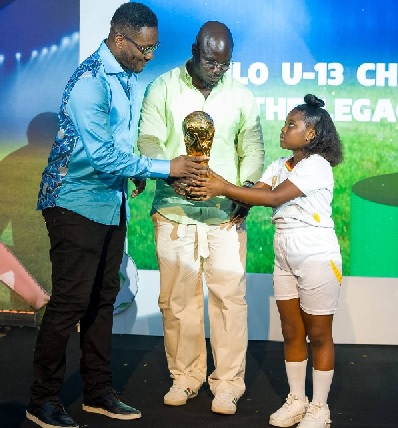 Asamoah Gyan (left) and Stephen Appiah, both ambassadors receiving the trophy at stake from a young model during the official launch of the 2026 edition