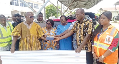 Ekow Okyere Eduamoah, (in smock) Central Regional Minister, handing over the items to representatives of the schools