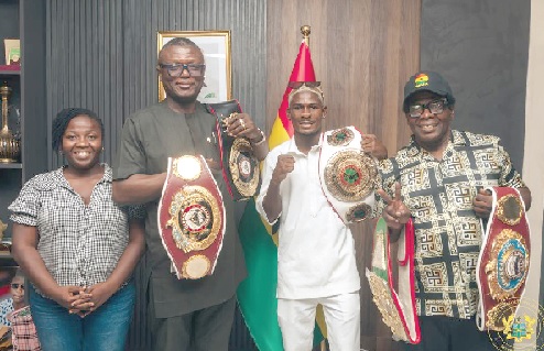 Kofi Iddie Adams (2nd from left) holds some of the title belts won by Theophilus Kpkpo Allotey during the boxers’s visit to the ministry alongside his trainer Kwasi Ofori Asare (right) and Sarah Lotus Asare (left) , the boxer’s manager