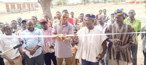 Stephen Aeke Akurugo (middle), DCE, Kassena Nankana West District, being supported by Naba Anthony Akurugo ll, Chief of Nyonga, to cut the tape to inaugurate one of the classroom blocks