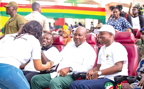 President John Dramani Mahama (2nd from right) and George Opare Addo (2nd from left), Minister of Youth Development and Empowerment   interacting with a beneficiary during the event