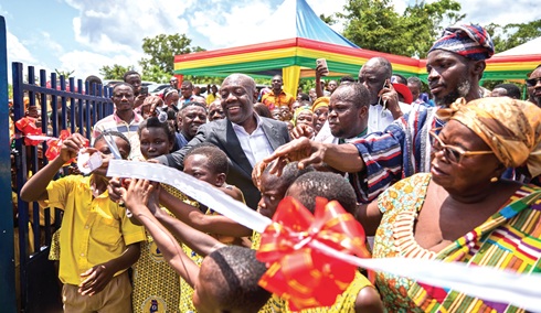 Kojo Oppong Nkrumah (arrowed), MP for Ofoase Ayirebi Constituency, being assisted by some leaders and schoolchildren to cut the tape to inaugurate the new school building