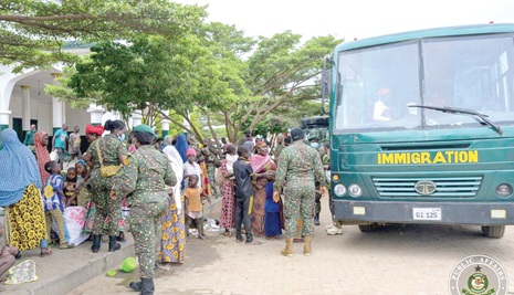 Immigration officers assisting beggars onto waiting buses as they clear them from the city