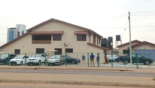 The pavement along the East Legon ARS Roundabout that has been encroached upon by the car dealership to display vehicles, forcing pedestrians to walk on gutter covers