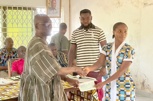 Peter Notsu-Kotoe (left), MP for Akatsi North, presenting a cheque to one of the student beneficiaries