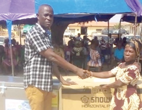 Modjifatanihu Jerry John Foreigner Mills-Nkrumah (left), Ada West District Chief Executive, presenting an item to a beneficiary 
