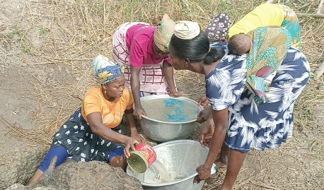 Some women fetching water from the unprotected natural well in Nyankpani. INSET: The unprotected well