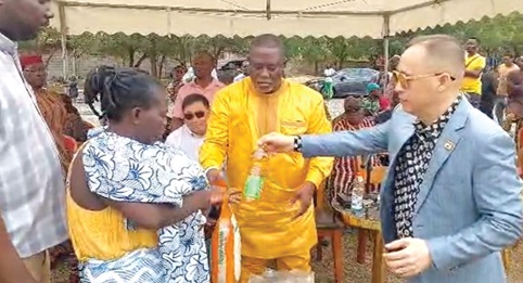 Tatse Nii Laryea Akuetteh X (middle), Chief of Katamanso, and Su Nyungkwon (right), Development Chief, Katamanso, presenting some of the items to a nursing mother 