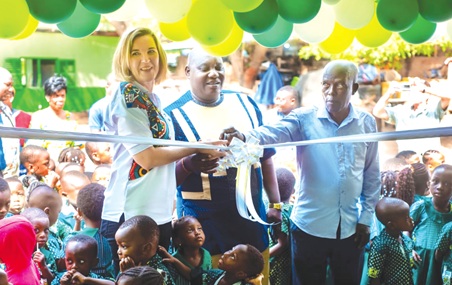 Madalene Smit (left) being assisted by  Mershak Annanthe, Headmaster, and Ebenezer Nartey the school administrator, to cut the ribbon to inaugurate the nursery (main picture)