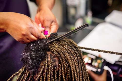 A hairstylist uses hair extensions to braid a client's hair. NickyLloyd/E+/Getty Images