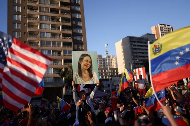 A person holds up an image depicting Venezuelan opposition leader Maria Corina Machado, as people celebrate after the U.S. struck Venezuela and captured its President Nicolas Maduro and his wife Cilia Flores, in Santiago, Chile January 3, 2026. REUTERS